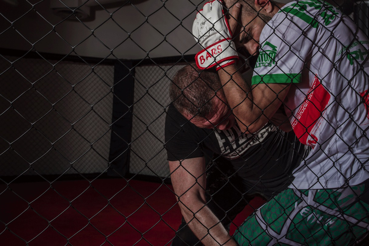 Vitaliy slamming his opponent against the wire fence of the MMA cage